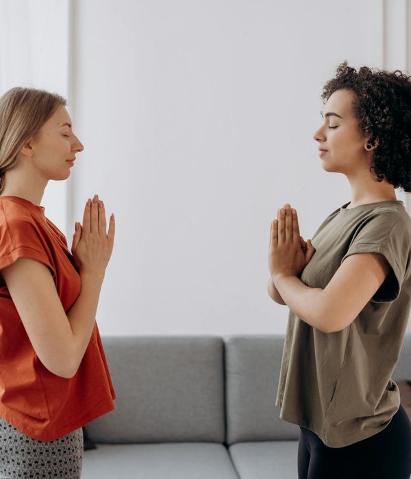 Woman in a peaceful yoga pose in a softly lit room.